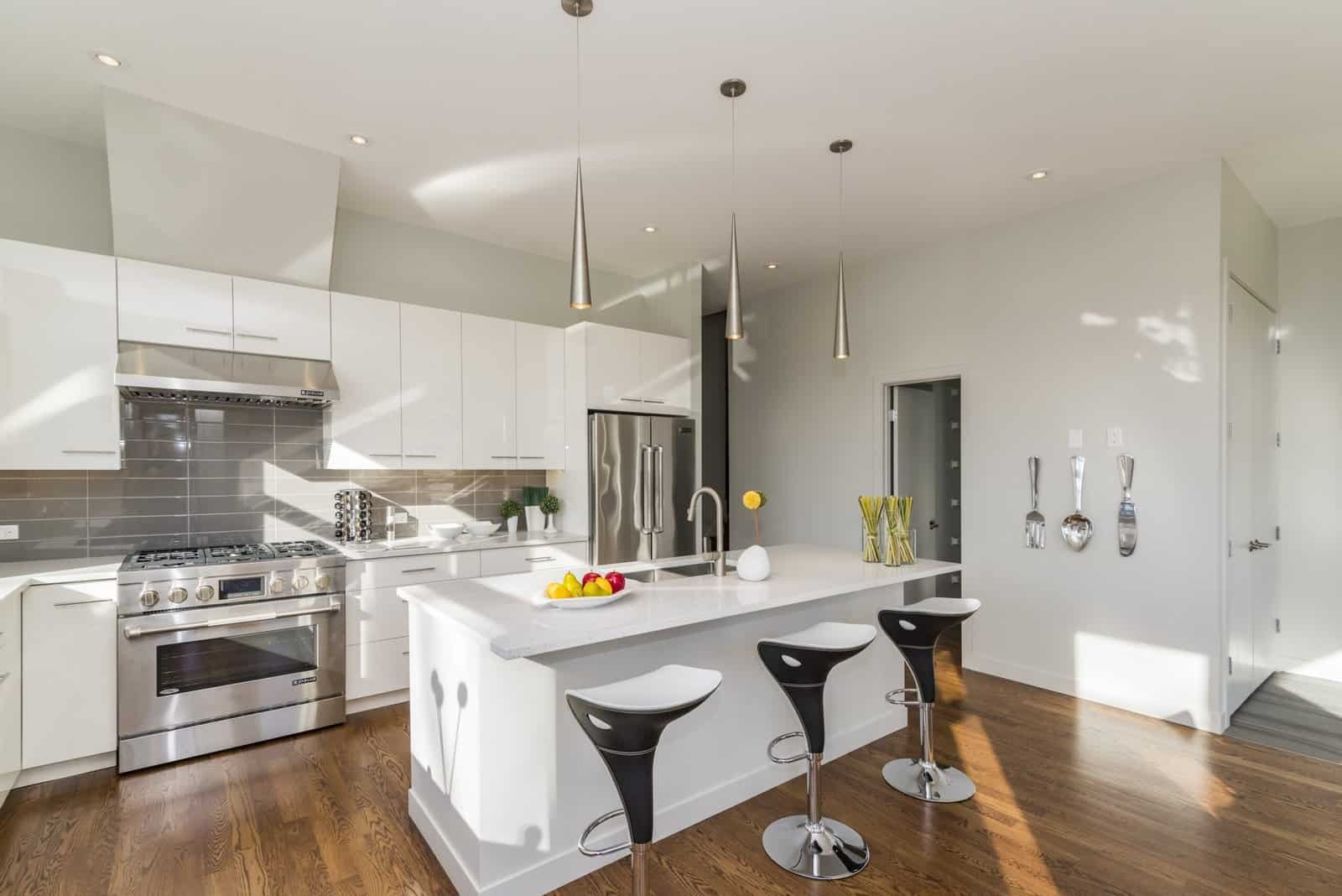 Modern Merced home kitchen with sleek white cabinetry and stainless steel appliances. Bright, contemporary kitchen with white cabinets, stainless steel appliances, and hardwood floors.