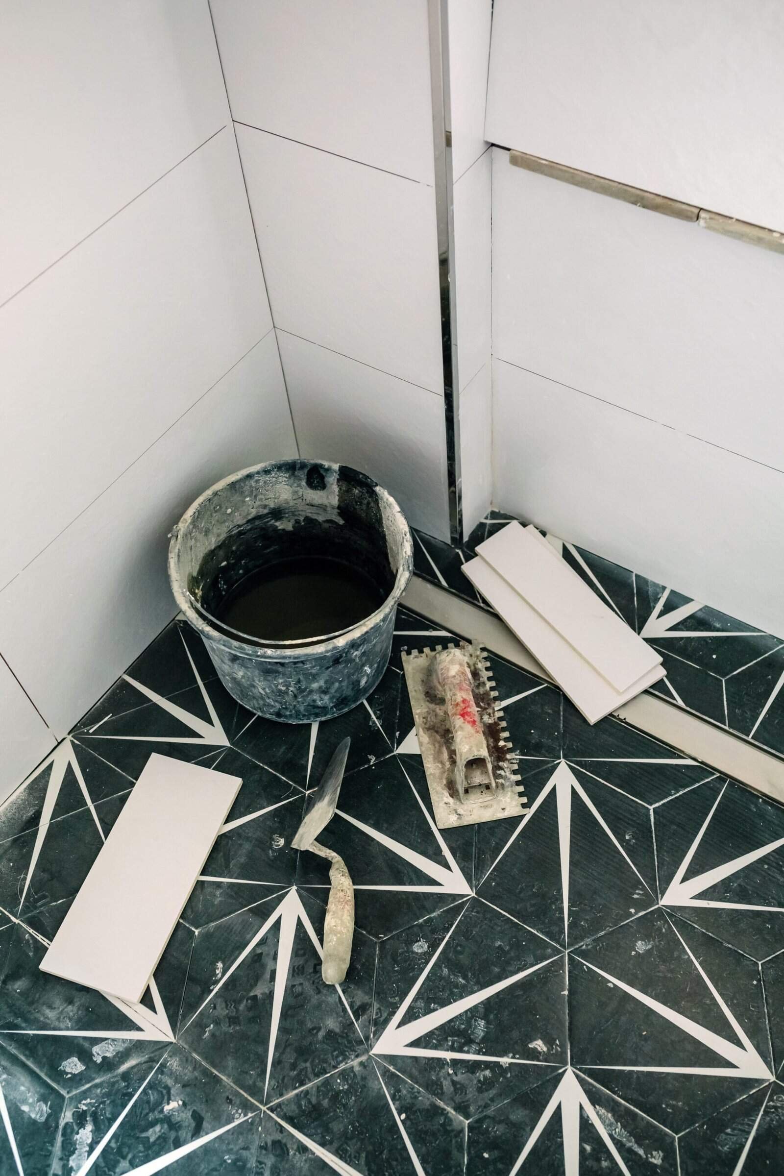 Bathroom tile installation by Merced Home Development Inc. showcasing black and white geometric floor design.